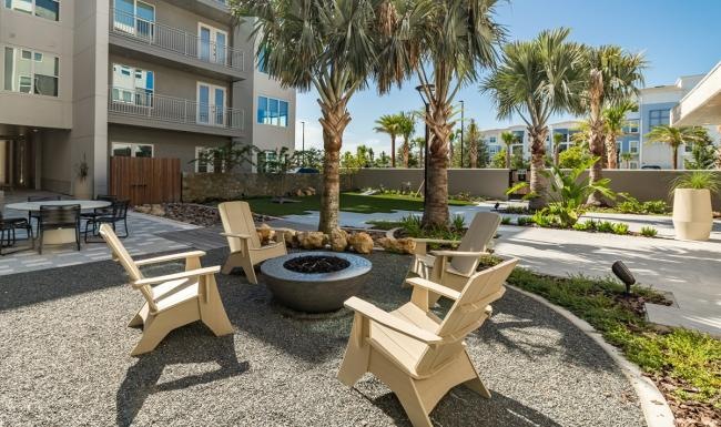 a courtyard with chairs and tables and palm trees